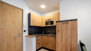 Eine Küche mit Holzausstattung, einer schwarzen Arbeitsplatte, einem Spülbecken und einem Herd.
