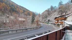 A winding road with a guardrail, surrounded by trees and a mountain in the background.