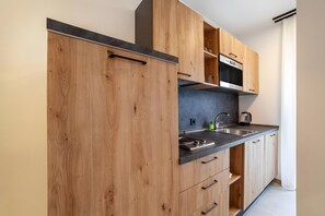A modern kitchen with wooden cabinets, a stainless steel sink, and a built-in oven.