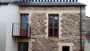 Un edificio de piedra con un balcón, una puerta y dos ventanas.