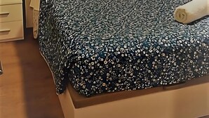 Un dormitorio con pared de piedra, una cama con colcha estampada, una mesita de noche y un buró.