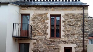 A stone building with a balcony, a door, and two windows. - Apartment 'Arriba' with Shared Terrace, Balcony and Wi-Fi (Afonsagrada)