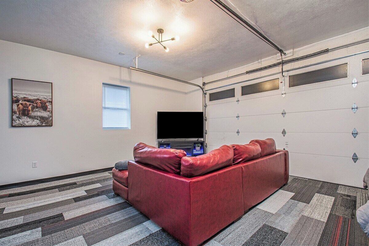 Un intérieur de maison moderne avec un canapé en cuir rouge, un téléviseur à écran plat et une porte de garage.