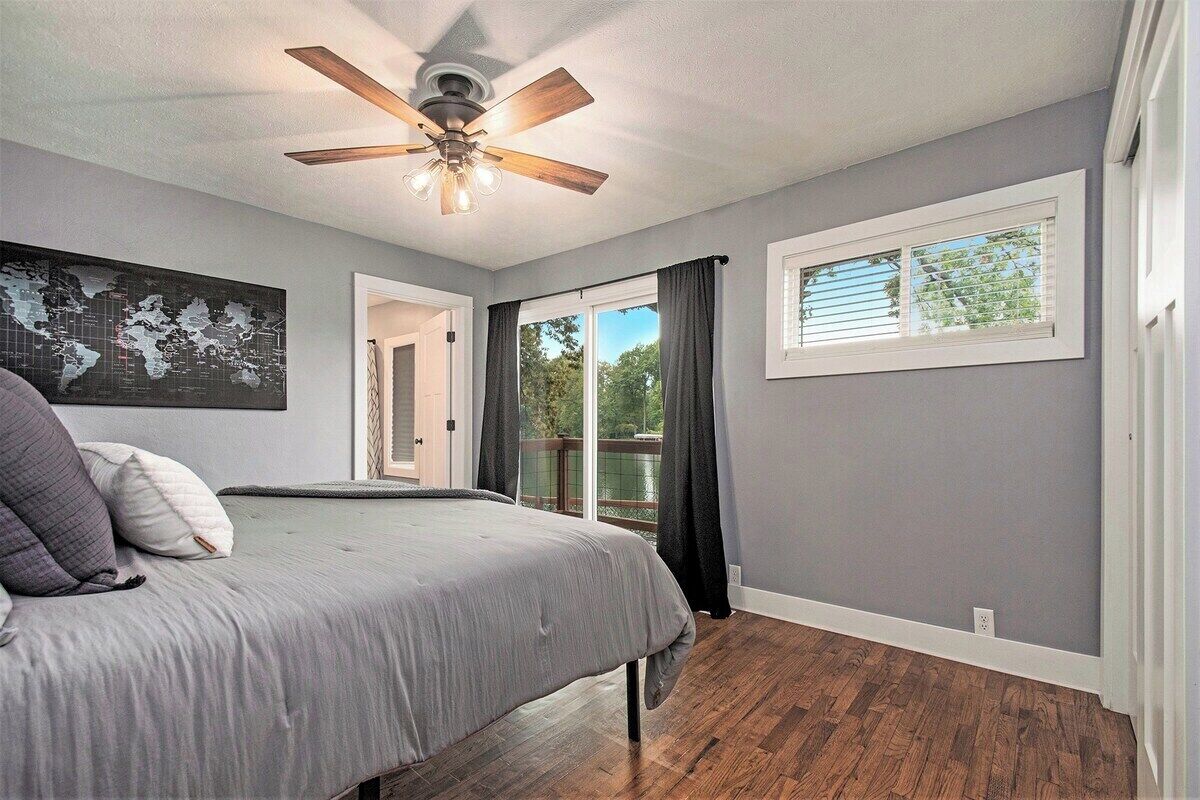 Une chambre à coucher avec un lit, un ventilateur de plafond, une carte du monde accrochée au mur et une fenêtre avec des rideaux.