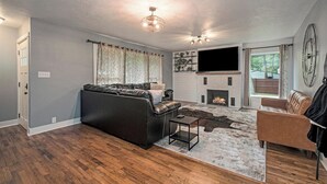 A modern living room with a fireplace, leather sofas, and a flat-screen TV.