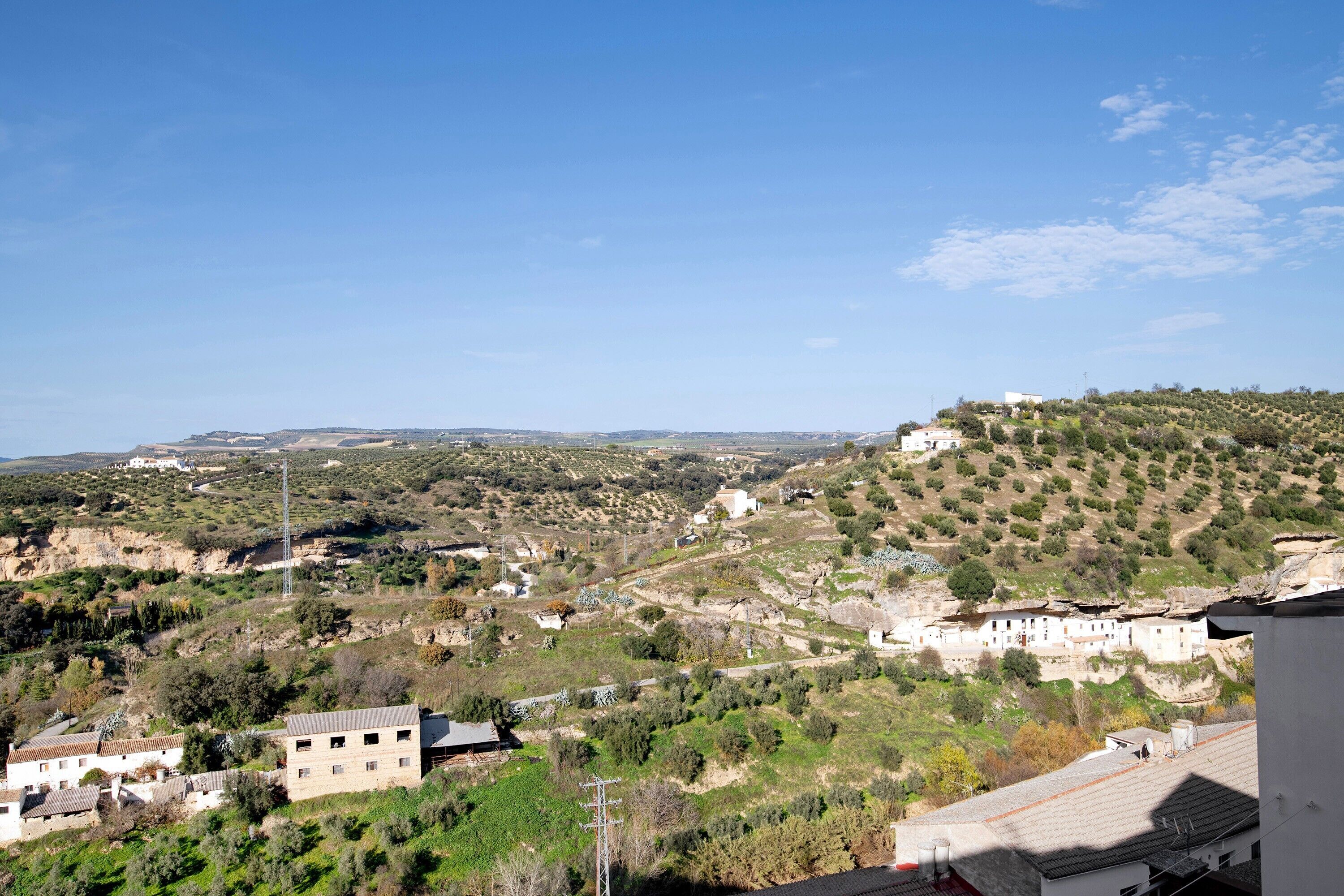 A rural landscape with buildings, a hill, and a clear sky.