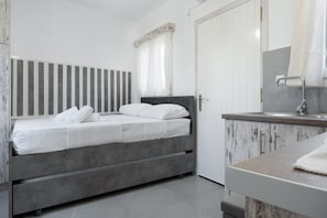A bedroom with a bed, a bedside table, a mirror, and a door. - Villa 'Christina 2 Kythnos' with Sea View, Wi-Fi and Air Conditioning (Driopida)