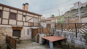 A traditional building with a stone facade, wooden balcony, and a small attached structure with a tiled roof.
