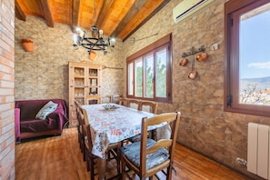 Un comedor rústico con pared de piedra, techo de madera y una mesa dispuesta para cuatro comensales.
