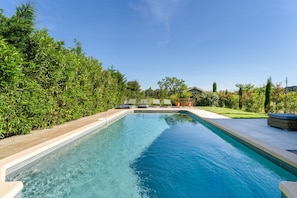 Et rektangulært pool med træterrasse på den ene side og græsplæne på den anden.