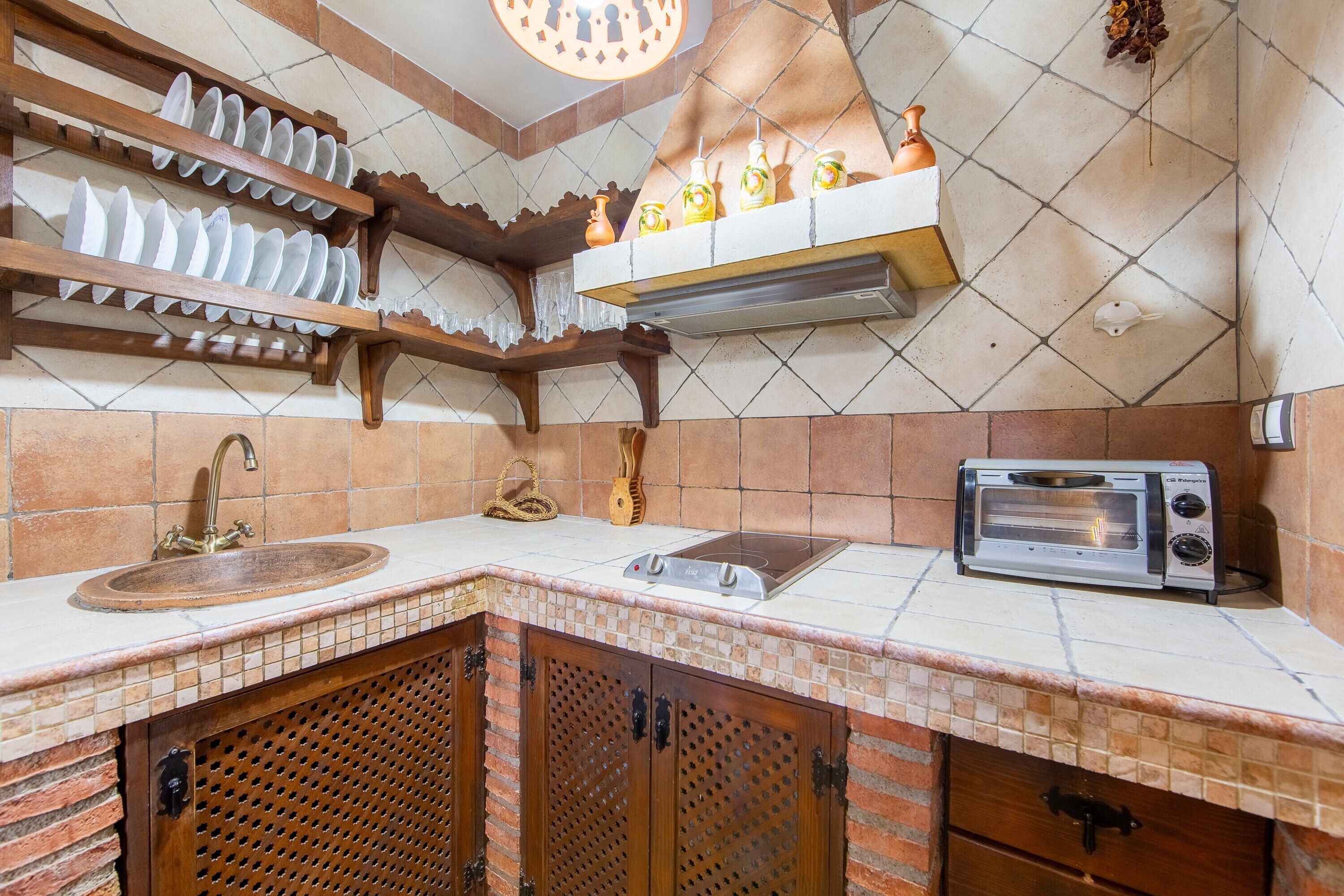Une cuisine équipée d’un évier, d’un grille-pain et d’une étagère suspendue où sont disposés des objets décoratifs.