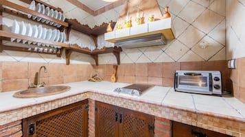 Une cuisine équipée d’un évier, d’un grille-pain et d’une étagère suspendue où sont disposés des objets décoratifs.
