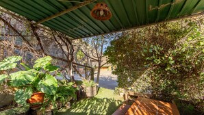 A covered outdoor area with a green roof, potted plants, and a tiled bench. - Casa Rural La Jirola - La Vivienda 1 with Mountain Views, Wi-Fi, and Air Conditioning (Abrucena)