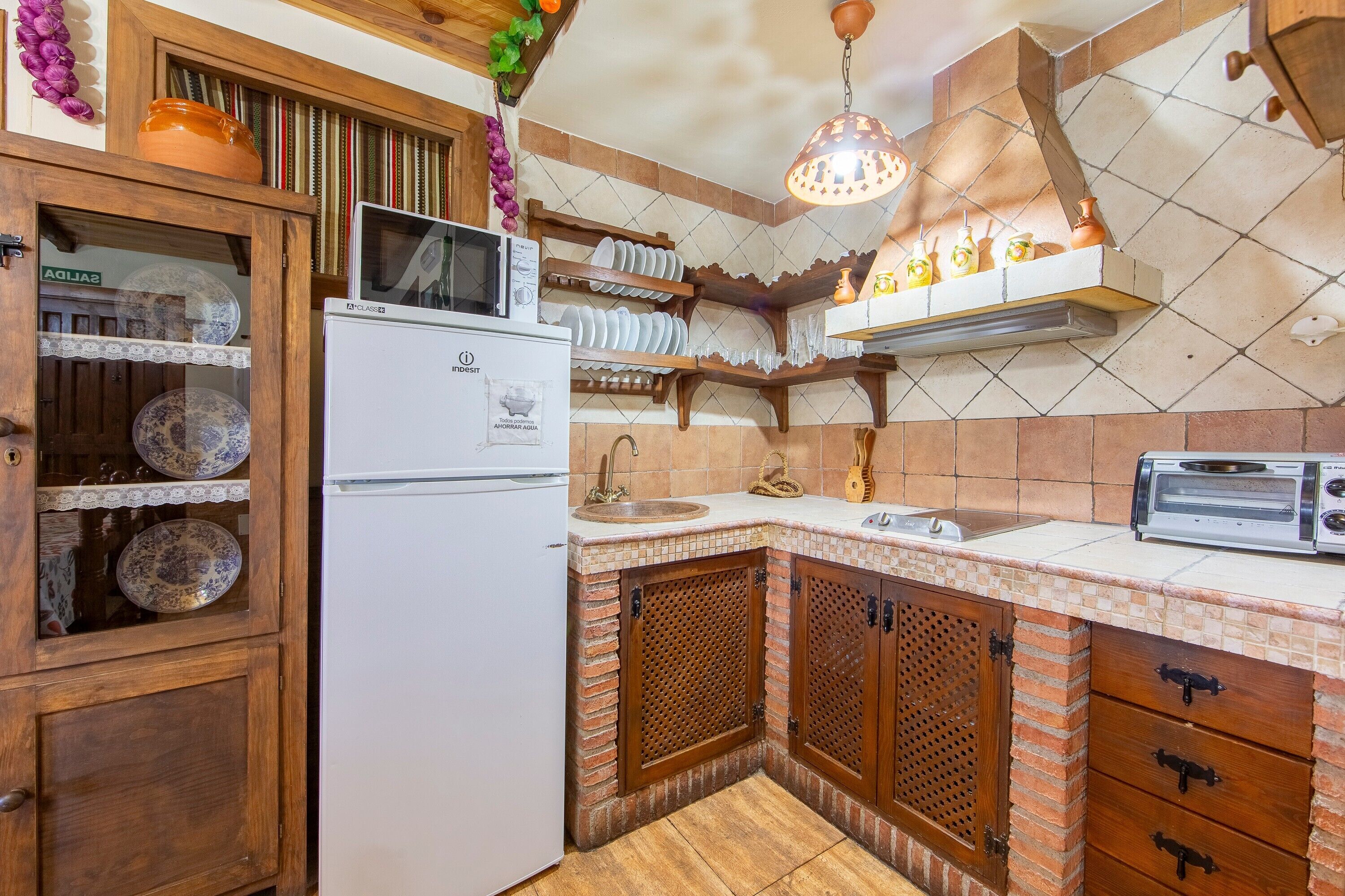 A kitchen with a refrigerator, microwave, sink, and a toaster.