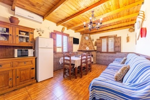 Un interior de madera con una mesa de comedor, sillas, un sofá, un refrigerador y un microondas.