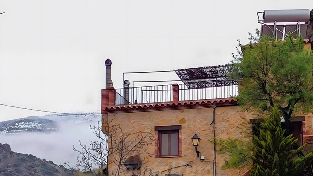 A stone building with a red door, a small window, and a balcony. - Casa Rural La Jirola -Vivienda 2 with Mountain Views, Wi-Fi, and Air Conditioning (Abrucena)