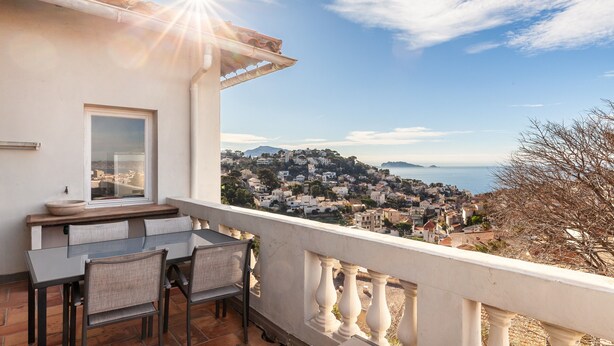Ein Balkon mit Tisch und Stühlen mit Blick auf eine Küstenstadt.