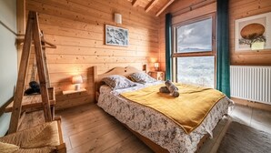 A wooden cabin bedroom with a bed, a ladder, a nightstand, and a window with a view. - Chalet 'Célestine 7 Bedrooms - Sauna' with Mountain View, Private Terrace and Wi-Fi (Verchaix)