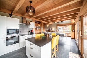 Uma cozinha moderna com armários brancos, uma ilha central e banquetas amarelas.