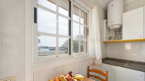 A kitchen with a window, a fruit bowl on the table, and a water heater.