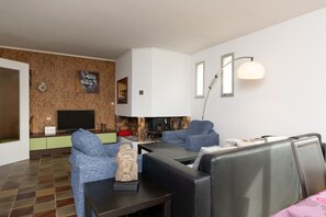 A modern living room with a flat-screen TV, a fireplace, and a sofa.