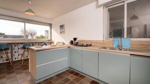 A modern kitchen with a large window, a sink, and a stove. - Holiday Home 'Maison Guidel Plage' with Sea View, Private Terrace and Wi-Fi (Guidel)