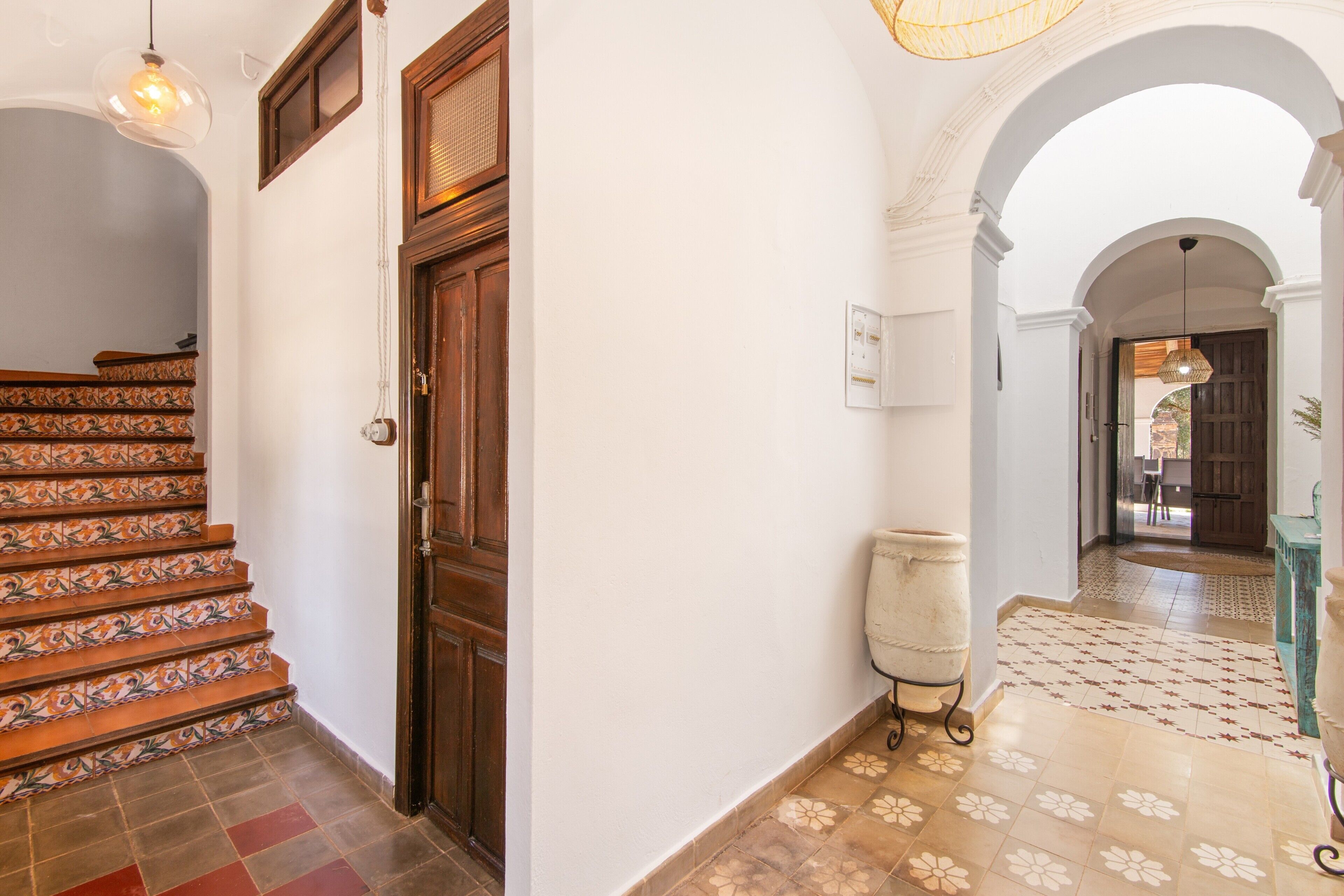 A staircase with patterned tiles, a wooden door, and a hallway with a patterned floor.