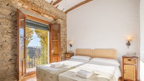 Ein Schlafzimmer mit zwei Betten, einer Steinwand, einem Balkon mit Geländer und einem kleinen Nachttisch mit Lampe.