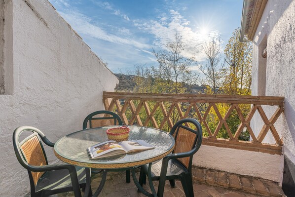 A round glass table with four wicker chairs, a wicker basket, and an open magazine.