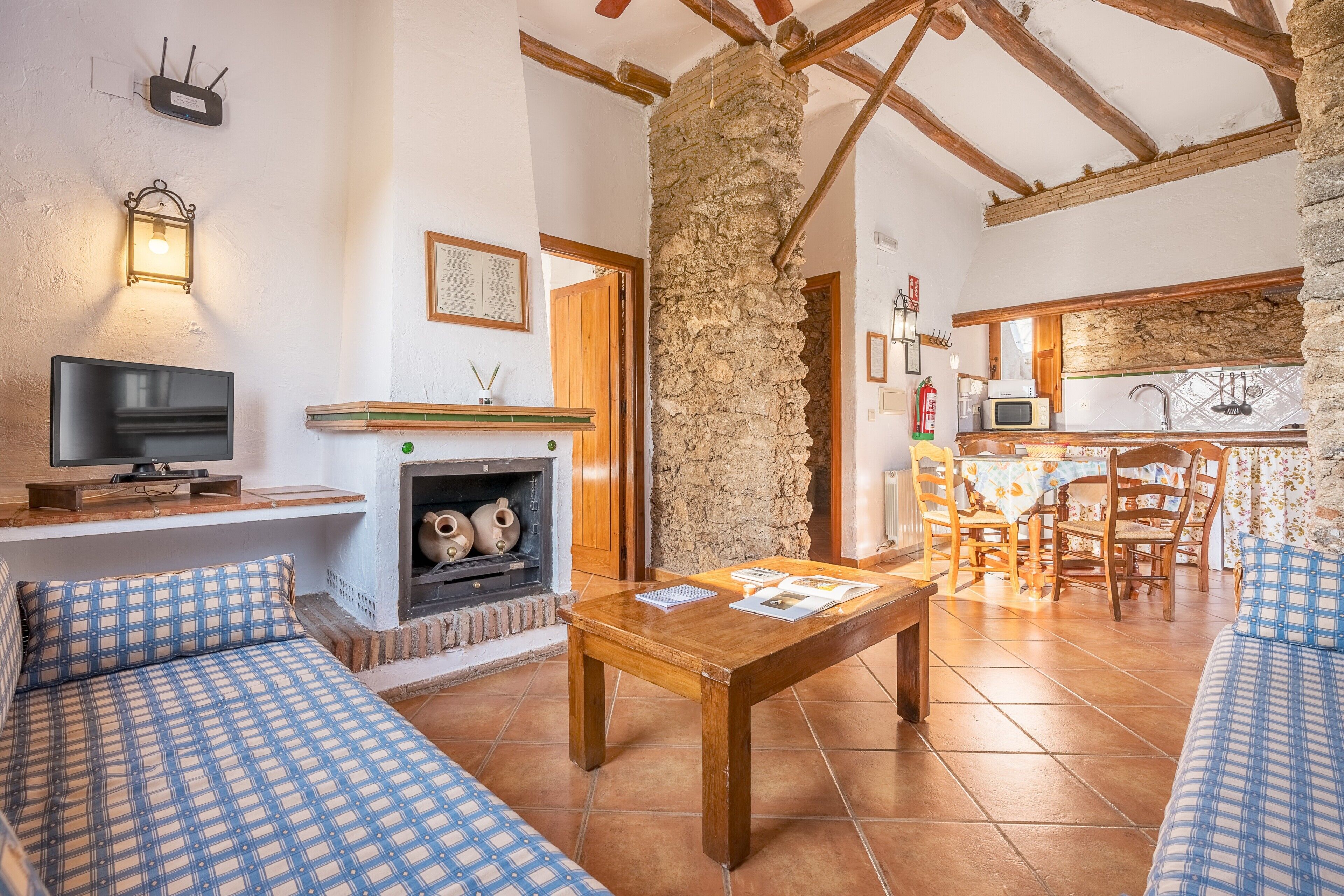 A cozy living room with a fireplace, wooden furniture, and a stone wall.