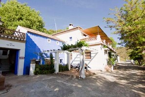 A building with a blue facade, a covered patio area, and a stone-paved entrance.