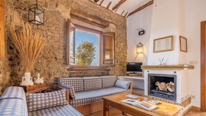 Ein gemütliches Wohnzimmer mit Steinwand, Kamin, Sofagarnitur und Fernseher.