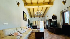 A living room with a sofa, a coffee table, a TV, and a chandelier. - Country House 'Can Conill Llucmajor' with Mountain View, Wi-Fi and Air Conditioning (Illes Balears)