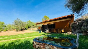 A house with a stone pond, outdoor seating, and a view of a field. - Country House 'Can Conill Llucmajor' with Mountain View, Wi-Fi and Air Conditioning (Illes Balears)