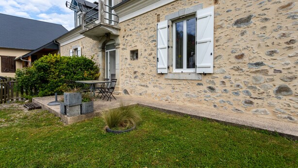 A stone house with a patio, a small garden, and a table with chairs. - La Maison de Tété – Charming Cottage near Lourdes, Private Terrace, Garden, WiFi (Artigues)