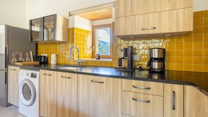 Una cocina moderna con lavadora, cafetera y ventana con vistas.