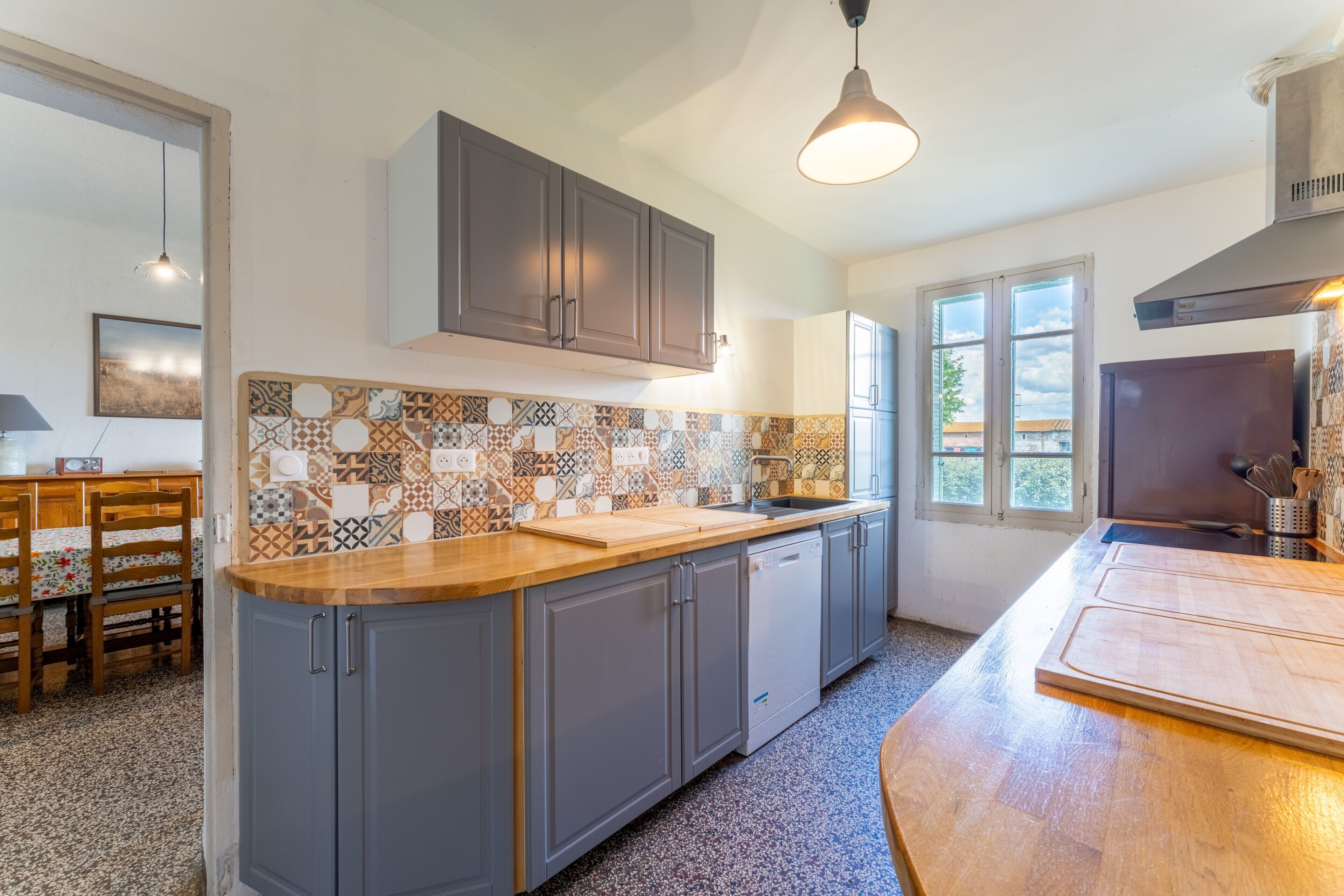 A kitchen with grey cabinets, a wooden countertop, and a tiled backsplash.