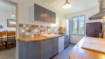 A kitchen with grey cabinets, a wooden countertop, and a tiled backsplash.