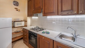 Una cocina con armarios de madera, microondas, estufa y lavamanos.