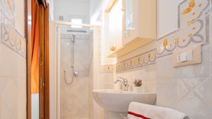 Un baño con ducha, lavamanos y barra para toallas.