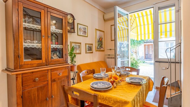 Comedor con un aparador de madera, una mesa servida con platos y vasos, y mantel amarillo.