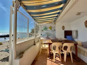 Een kamer aan het strand met uitzicht op zee, een eethoek met tafel en stoelen, en een muurschildering.