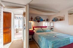 Een slaapkamer met een bed, een deur, een raam en uitzicht op het omliggende landschap.