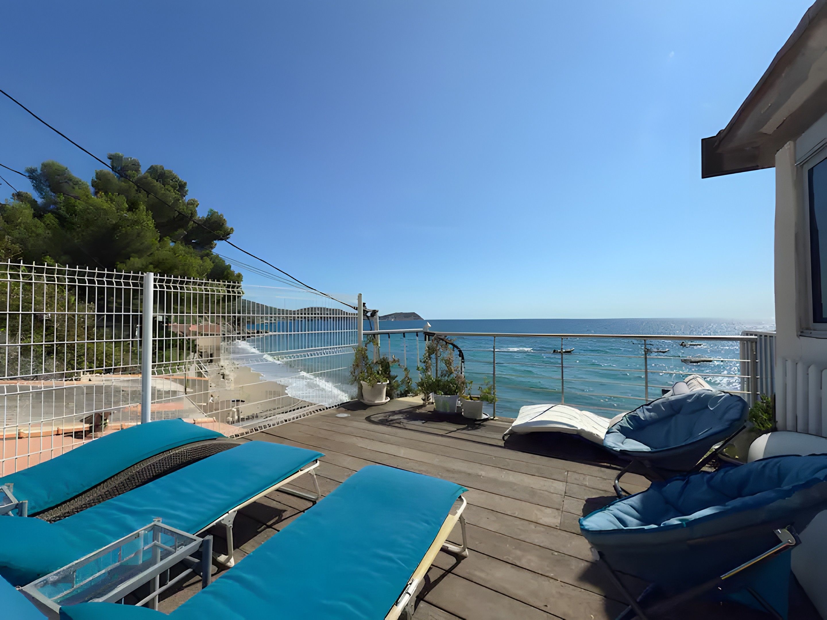Een balkon met uitzicht op zee, voorzien van ligbedden en een klein tafeltje.