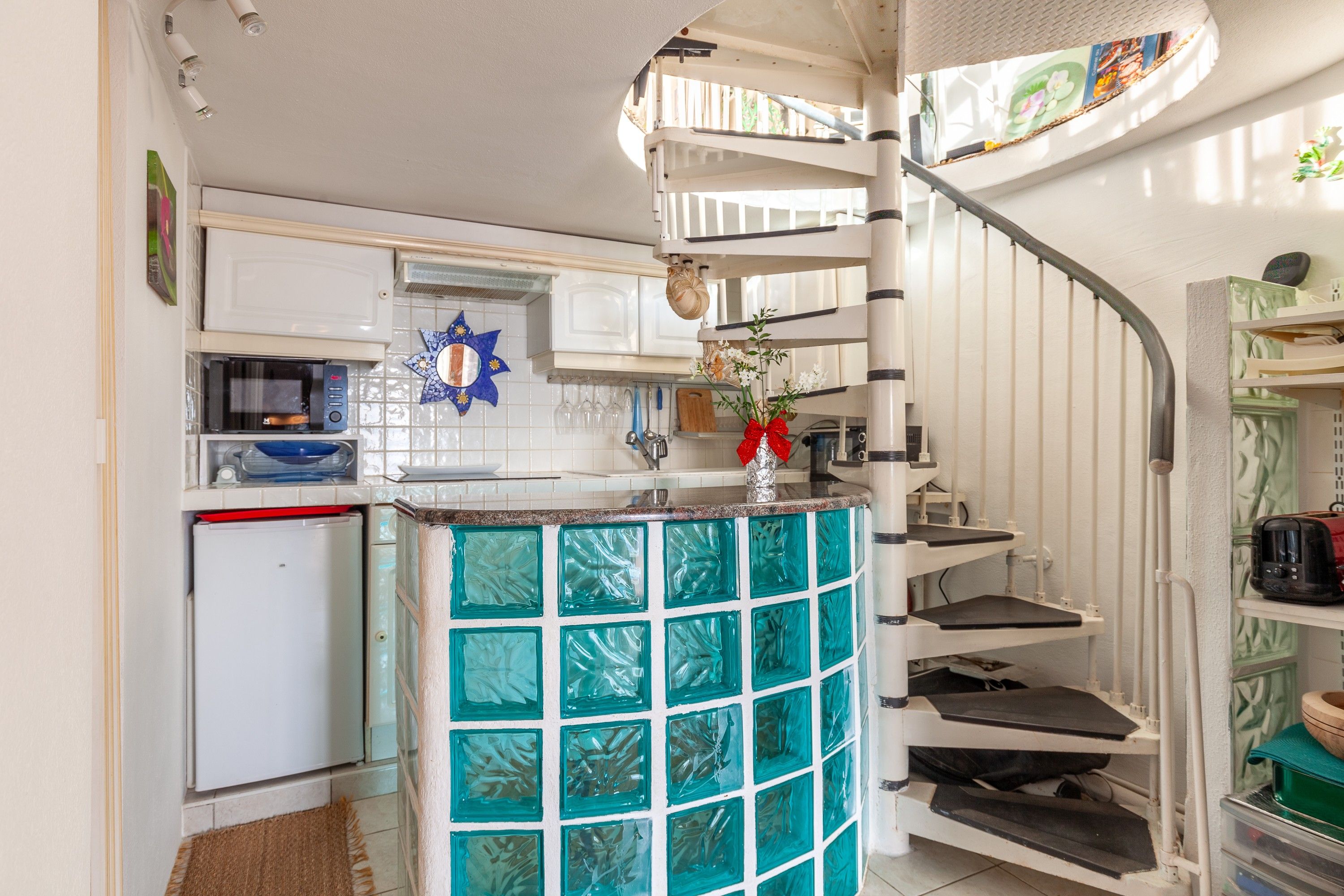A kitchen with white cabinets, a microwave, and a small refrigerator.