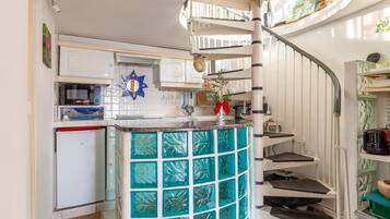 A kitchen with white cabinets, a microwave, and a small refrigerator.