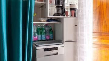 Eine kompakte Küchenzeile mit Kaffeemaschine, kleinem Kühlschrank und Wasserspender.