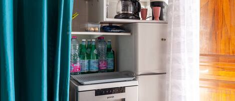 A compact kitchenette with a coffee maker, a small refrigerator, and a water dispenser.