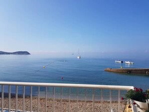 Vista costera con playa arenosa, mar azul cristalino y algunas embarcaciones.