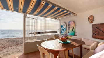 Um alpendre à beira-mar com uma mesa, cadeiras e vista para o mar.